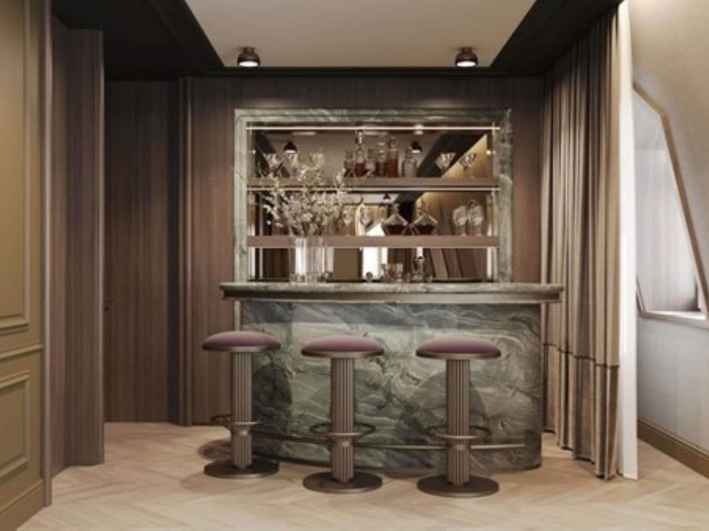 A bar area with marble countertop, stools, and shelves with bottles.