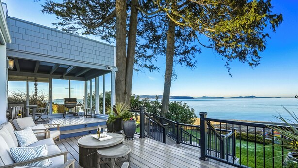 Eine Terrasse mit Gartenmöbeln, einem Esstisch und Blick aufs Meer.