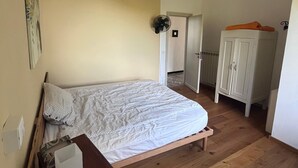 Een slaapkamer met een houten bed, een nachtkastje, een kledingkast en een hanglamp.