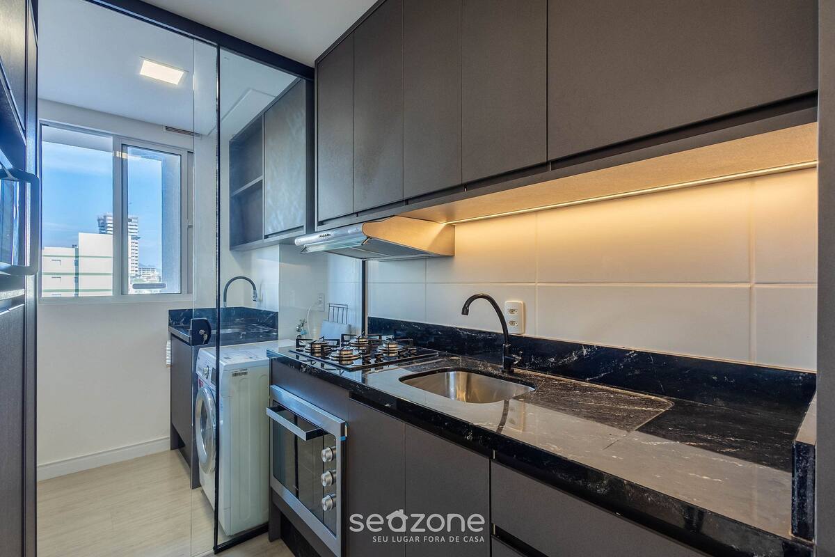 Eine moderne Küche mit Einbauofen, Spüle und Fenster mit Blick auf die Stadt.