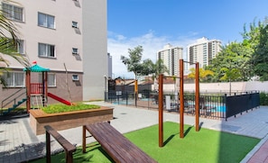 Ein Spielplatz mit Rutsche, Klettergerüst und Kunstrasen.