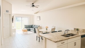 A modern kitchen with a granite countertop, white cabinetry, and a built-in dishwasher. - Spacious 3-Bedroom Getaway — Perfect for Families or Groups!” (Cape Coral)