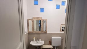 Un baño con lavamanos, espejo, inodoro y baldosas de suelo con diseño.