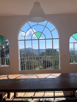 A room with a large arched window overlooking a mountainous landscape.