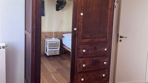 Un armario de madera con varios cajones y un espejo, ubicado en una habitación con piso de madera y una puerta blanca.
