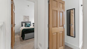 Een slaapkamer met een bed, een nachtkastje en een spiegel aan de muur.