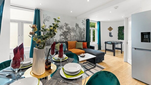 A modern living room with a dining area, a sofa, a coffee table, and a foosball table. - Boutique Bristol Abode - Games Room (Bristol)