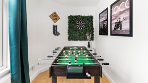 A foosball table in a room with a dartboard, a 'GAME ZONE' sign, and Prada and Coco-themed posters on the wall. - Boutique Bristol Abode - Games Room (Bristol)
