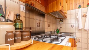 A kitchen with a gas stove, wooden cabinets, and a tiled backsplash.