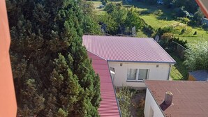 Un quartier résidentiel avec une maison dotée d’un toit rouge, entourée d’une végétation luxuriante et sous un ciel dégagé.