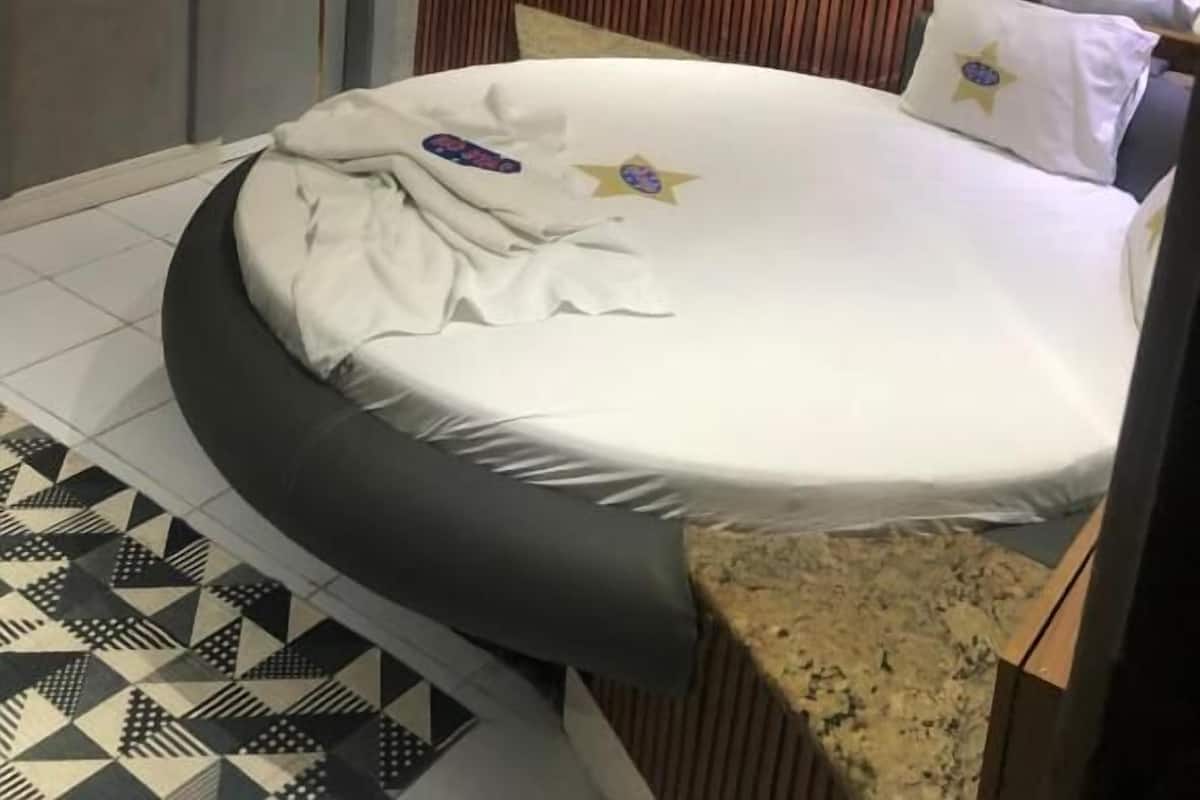 A modern bedroom with a round bed, striped wall paneling, and a geometric tile floor.