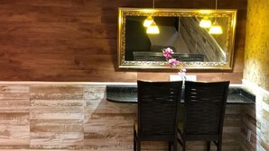 A bathroom with a wooden wall, a large mirror, two chairs, and a small table.