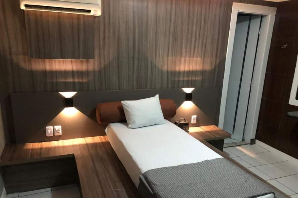 A modern hotel room with a bed, two bedside tables, and a nightstand.