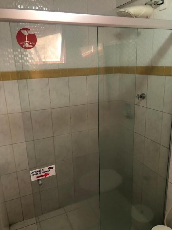 Cabina de ducha con paredes de vidrio y un letrero que indica una característica de seguridad.