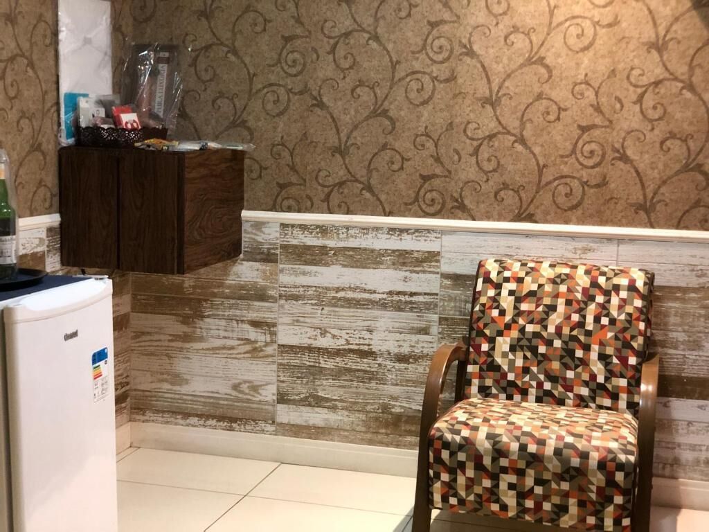 A kitchen with a patterned wall, a wooden cabinet, and a chair with a geometric pattern.