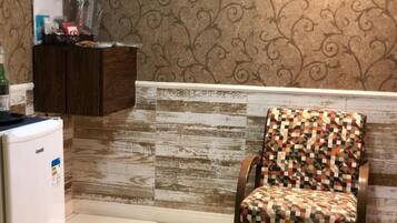 A kitchen with a patterned wall, a wooden cabinet, and a chair with a geometric pattern.