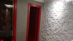 A bedroom with a bed, a red door, and a tiled wall.