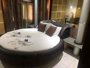 Una cama redonda con un colchón blanco, dos almohadas y una toalla.