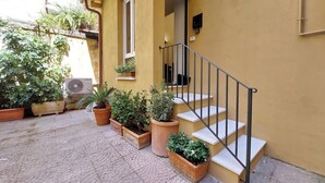Ein gelbes Gebäude mit Treppe, Blumentöpfen und einer Klimaanlage.