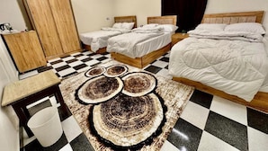 A hotel room with two single beds, a wooden wardrobe, a desk with a chair, and a checkered floor. - Great Pyramids Lodge (Giza)