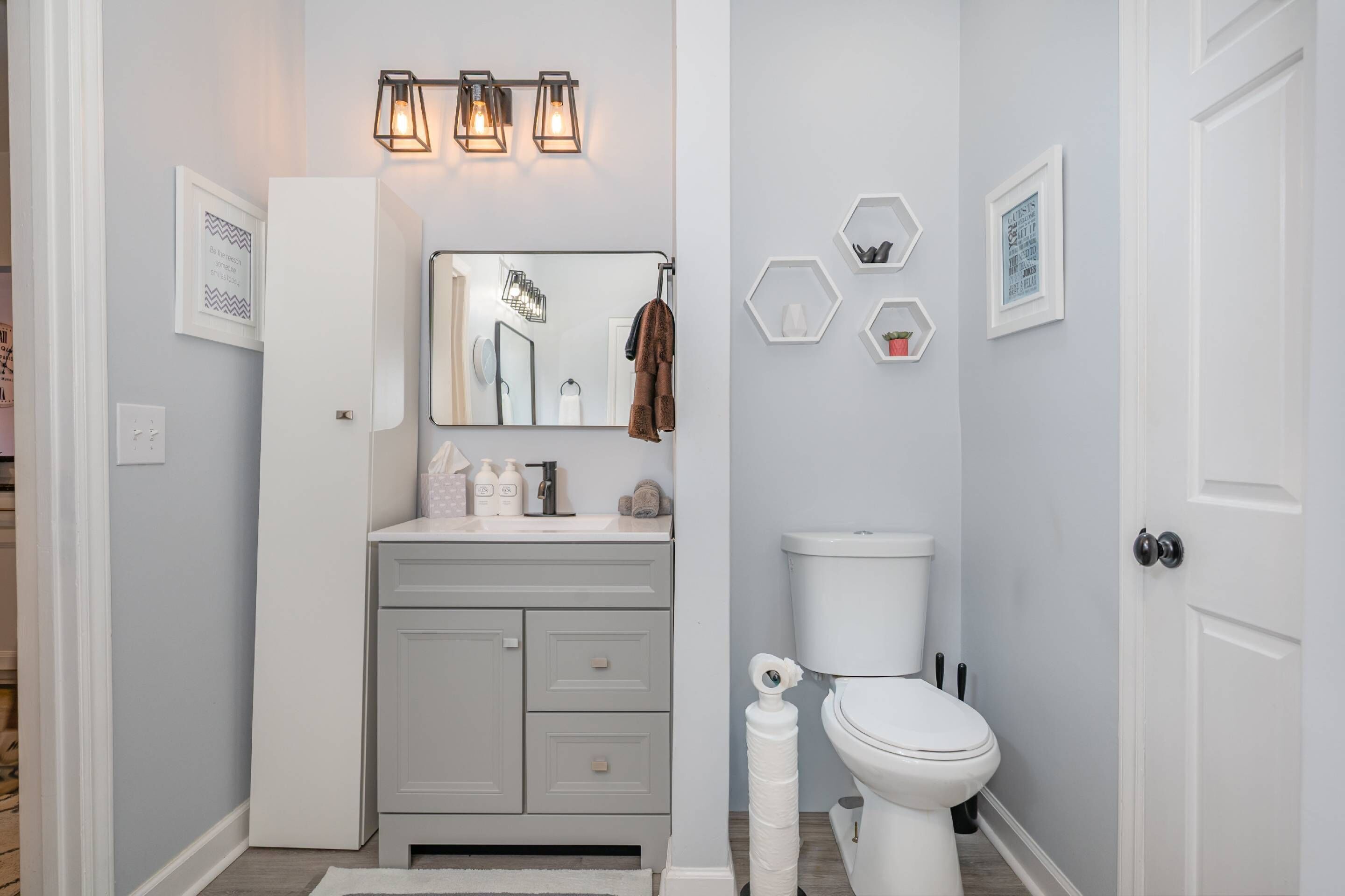 A bathroom with a white vanity, a mirror, a toilet, and a shower area.