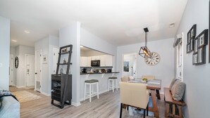 A modern kitchen with white cabinets, a central island, and a dining area with a wooden table and chairs.