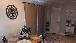 A dining area with a round table, four chairs, a decorative wall piece, and a door in the background. - Charming 3-bedroom house with AC in nice Hope Hull. (hope hull)