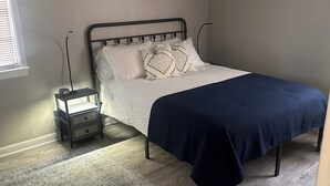 A bedroom with a bed, a nightstand, a floor lamp, and a rug. - Charming 3-bedroom house with AC in nice Hope Hull. (hope hull)