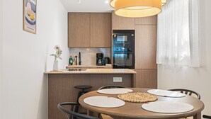 Une cuisine moderne avec des meubles en bois, un four encastré et une machine à café.