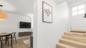 Un intérieur moderne comprenant un coin repas, un escalier et une œuvre d’art accrochée au mur.
