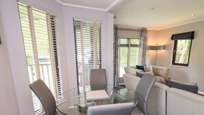 Un salon moderne avec une table en verre entourée de chaises, d’un canapé et d’une lampe.