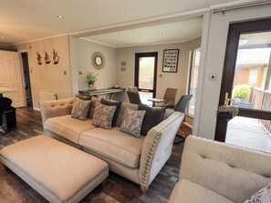 A living room with a sofa, ottoman, and a dining area with a table and chairs.