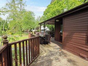 A wooden deck with a railing, a covered seating area, and a building entrance.