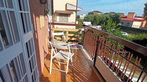 Ein Balkon mit Fliesenboden, einem weißen Metallgitter und einem Holzzaun.