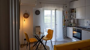 Eine kompakte Küche mit Essbereich, ausgestattet mit einem Kühlschrank, einer Mikrowelle, einem Herd und einem kleinen Tisch mit Stühlen.