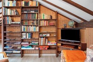 A room with wooden bookshelves filled with books, a television, and a globe. - Haus Palais with Covered Balcony, Mountain View, and Wi-Fi (Münstertal)