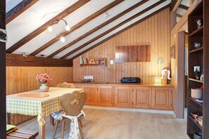 A kitchen with wooden cabinets, a table with a checkered tablecloth, and a chair with a heart-shaped cushion. - Haus Palais with Covered Balcony, Mountain View, and Wi-Fi (Münstertal)