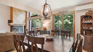 A dining area with a wooden table, chairs, and a hanging light fixture.