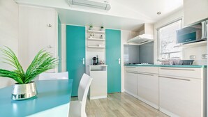Une cuisine moderne avec des meubles blancs, un plan de travail de couleur turquoise et une plante en pot.