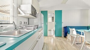 Une cuisine moderne équipée d’un évier, d’un four à micro-ondes et de placards, qui donne sur un coin repas avec une table et des chaises.
