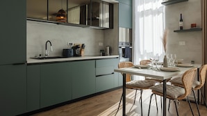 Una cocina moderna con comedor, que cuenta con un amplio ventanal, armarios empotrados y una lámpara colgante.