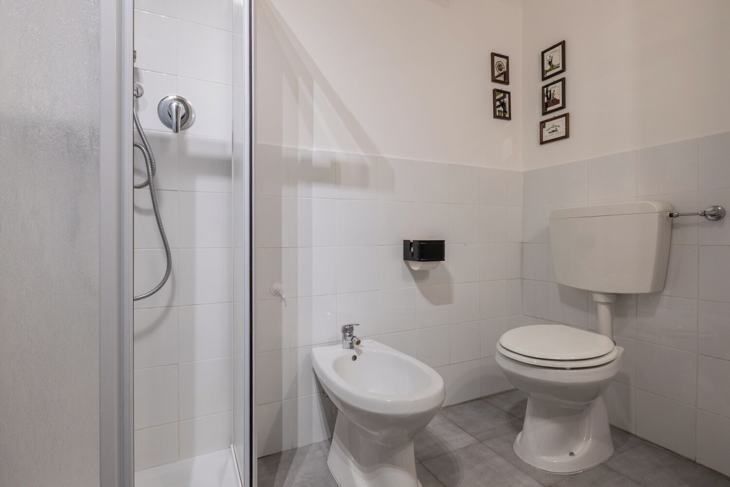 A bathroom with a glass shower enclosure, a bidet, and a toilet.