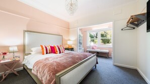 A bedroom with a large bed, bedside tables, a bench, and a wardrobe.