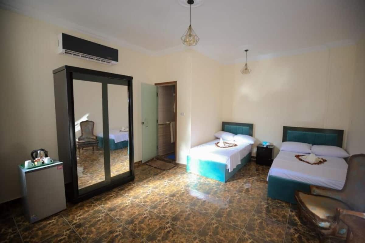 A hotel room with two beds, a wardrobe, a desk, and a mirror.