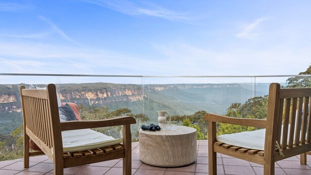 A balcony with two wooden chairs and a small round table, overlooking a canyon landscape. - Jamburra - Breathtaking views of the Blue Mountains! (Leura)