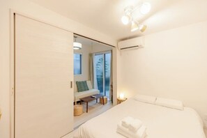 A hotel room with a bed, a sofa, a small table, and a mirror. - Mi-Ochiai Soluna White (Tokyo)