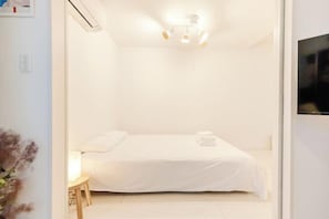 Une chambre à coucher avec un lit, une table de chevet et un téléviseur fixé au mur.