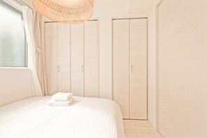 A bedroom with a bed, a window with curtains, a hanging light fixture, and a wardrobe. - Mi-Ochiai Soluna White (Tokyo)
