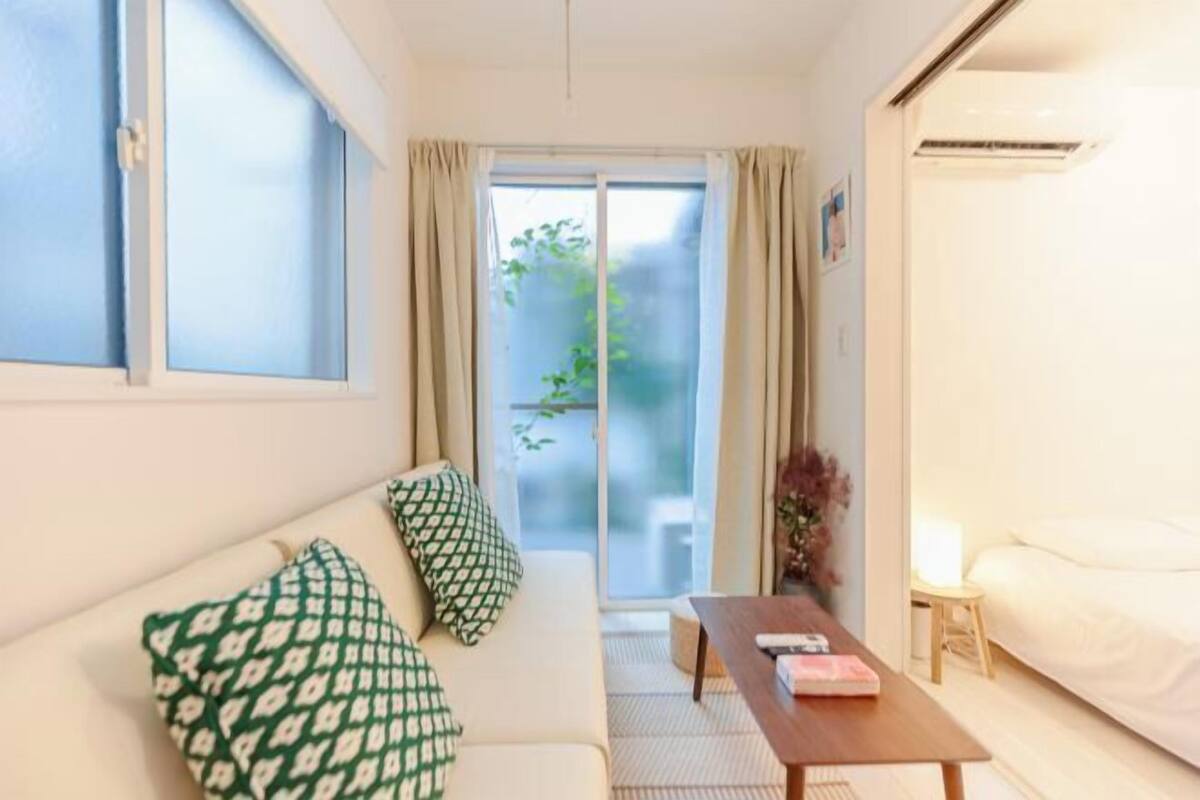 Habitación de hotel compacta con sofá, una mesita, cama y puerta corrediza de vidrio que da a un balcón.