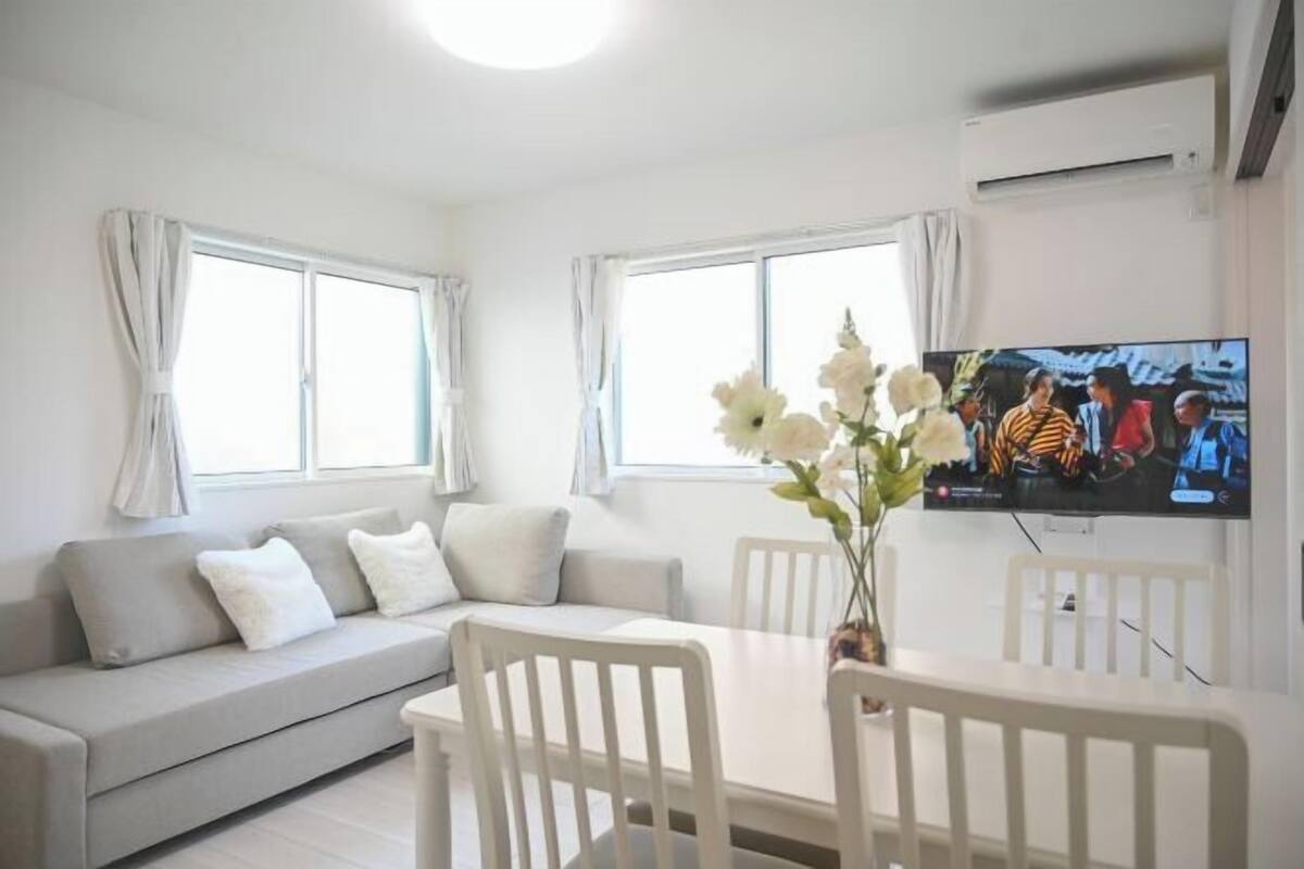 Una sala de estar moderna con un sofá, una mesa de comedor, sillas y un televisor.